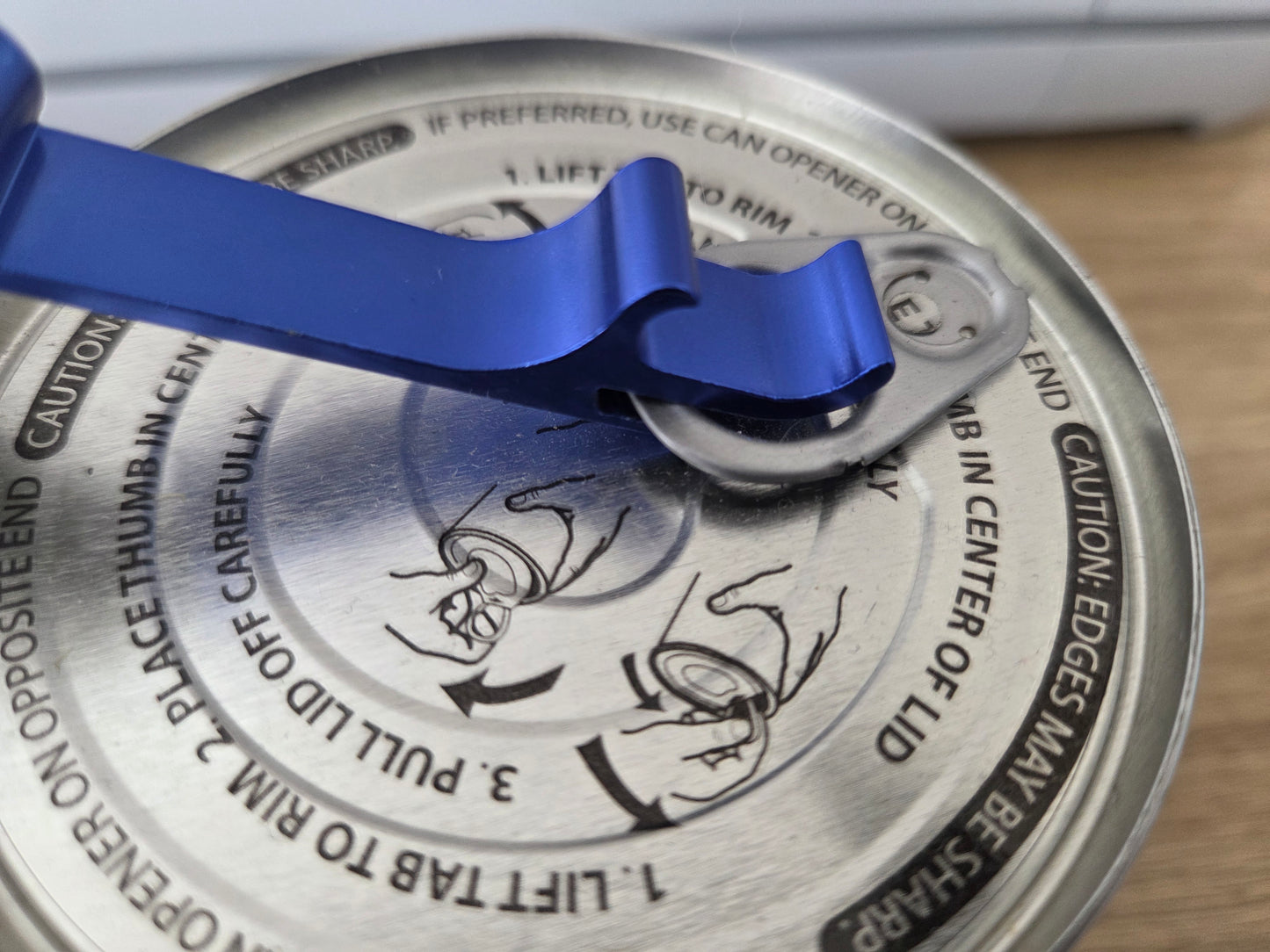 Can opener on a can lid with blue handle